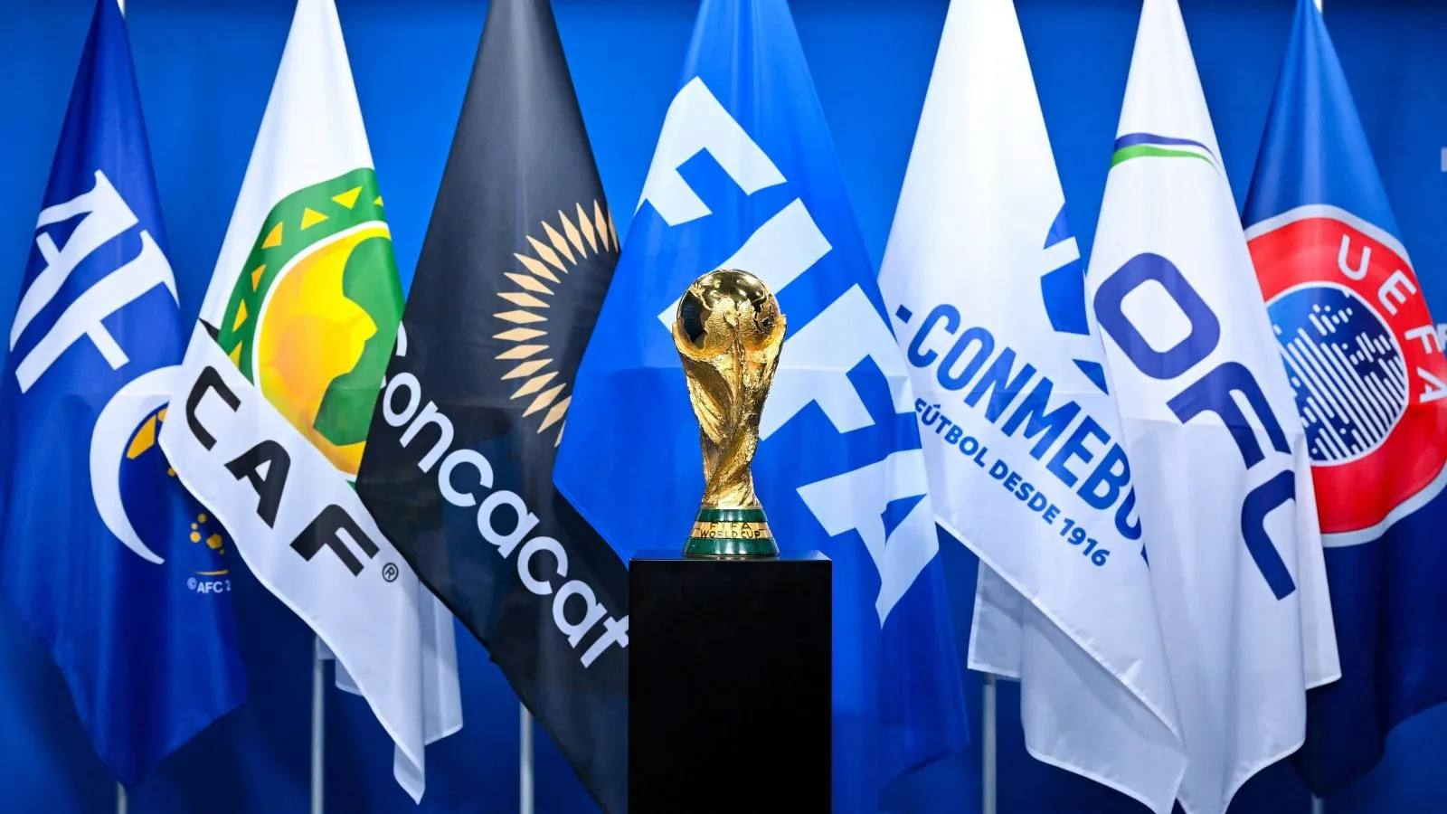 Trophée du Mondial 2030 à 64 équipes devant les drapeaux des organisateurs